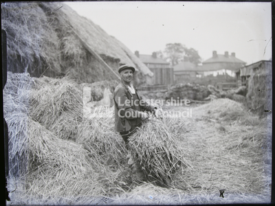 Man holding hay bundle in farmyard		