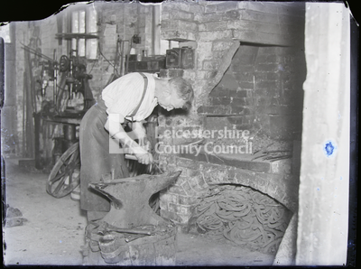 Blacksmith shaping hook on anvil