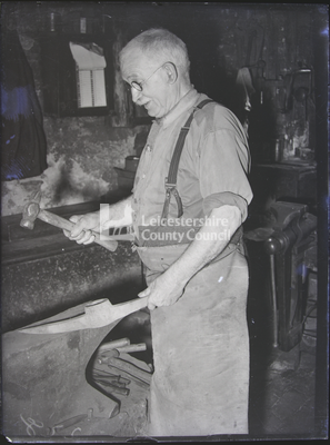 Blacksmith shaping pick-head on anvil		