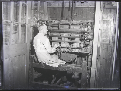 Man in white coat operating knitting 'needler' machine