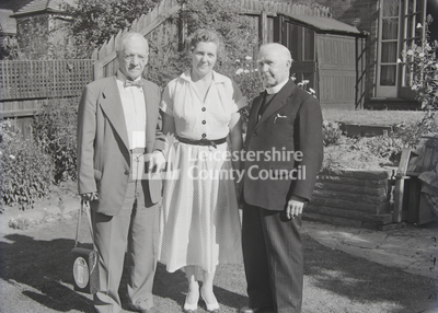 Dr Williams, wife and cleric standing together in garden	