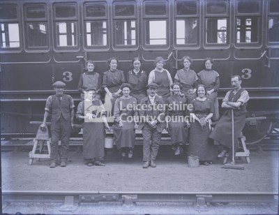 Group portrait of railway cleaners in front of train