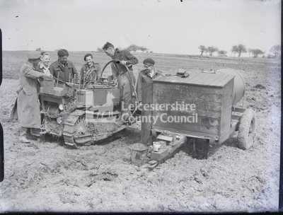 Six people in uniform with tractor and other farm equipment