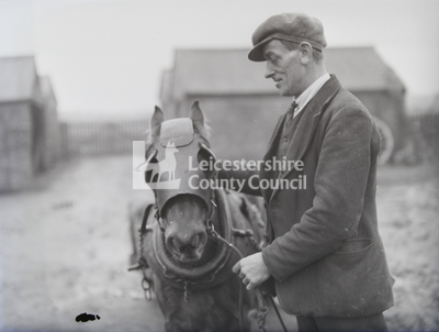 man with pony outside farm buildings	