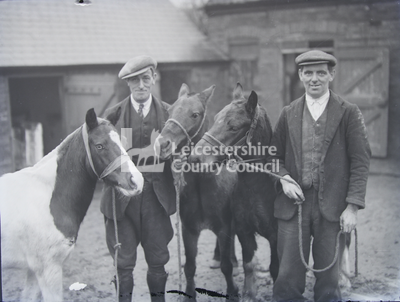 2 men in stable yard with 3 ponies