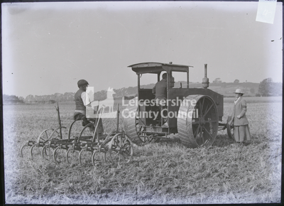 2 men operating Mogul tractor with reaper, 