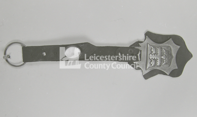 leather attachment with horse brass (solid holly-leaf shape with shield coat-of-arms inside)		