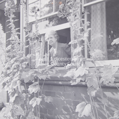 Elderly lady leaning out of window, from garden