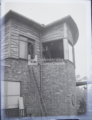 House with upper windows blasted; man in window