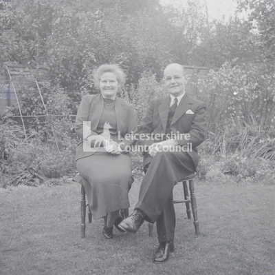 Older couple seated in chairs in yard	