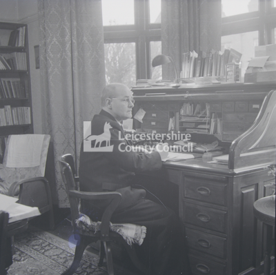 Man seated at large writing desk 