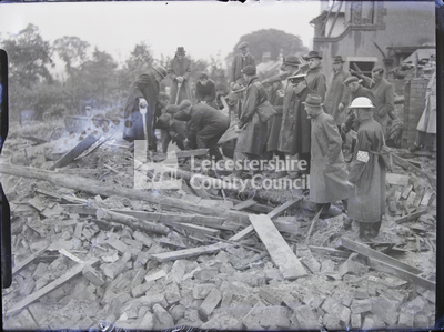 Earl Shilton Bombing: Large group standing over building rubble, pulling something out