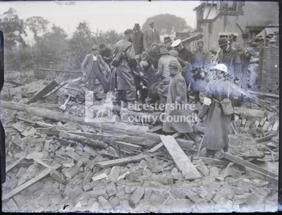 Earl Shilton bombing: Large group standing over building rubble, pulling something out