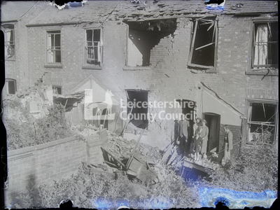 Family of five at doorway of damaged apartment and yard