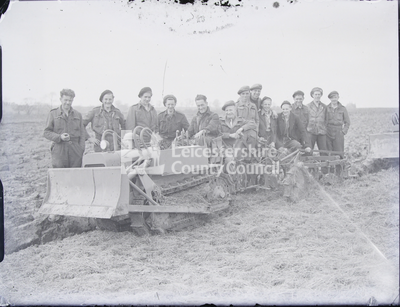 Men in uniform standing with plough